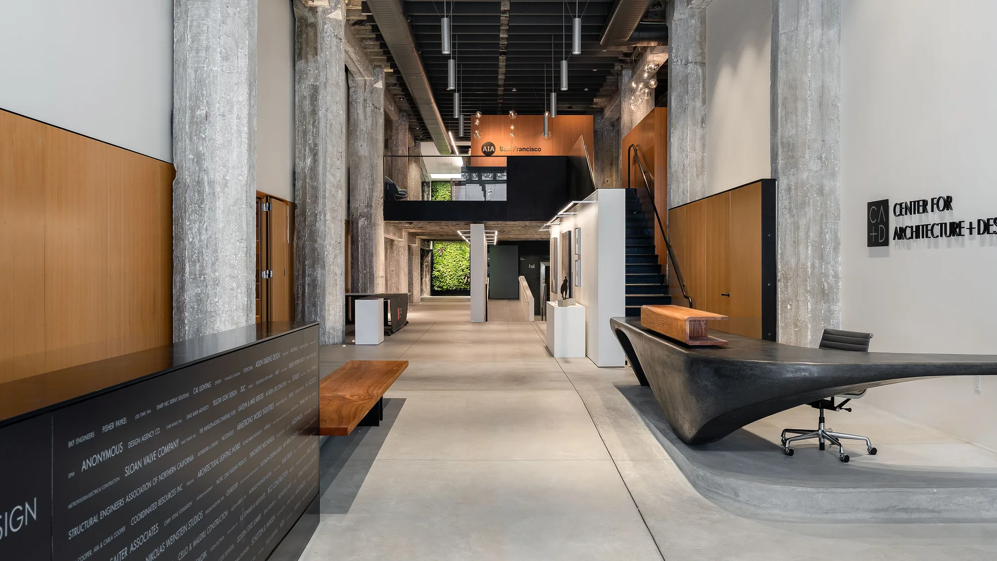 The same gallery finished: the corridor running its full length between concrete columns, the AIA San Francisco mezzanine at the far end