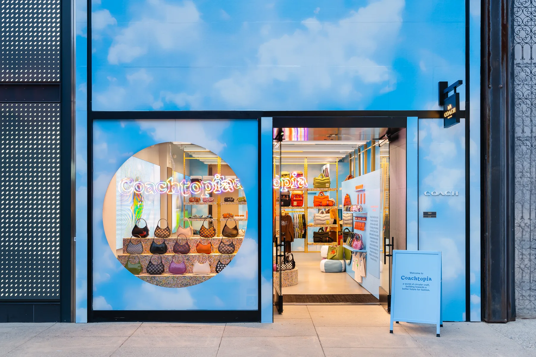 The Coachtopia entrance: the printed cloud facade open to the shop floor, a circular Coachtopia graphic across the glass