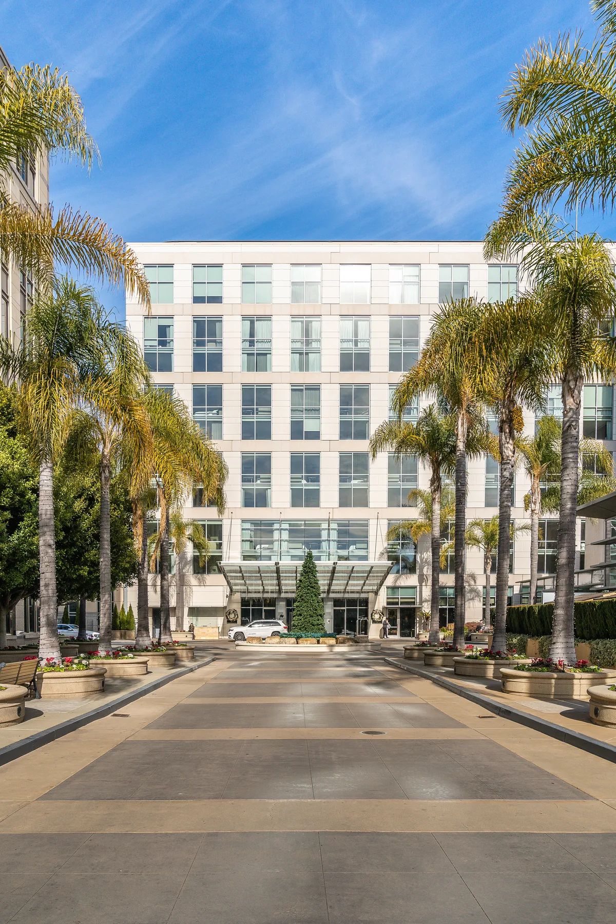 The Four Seasons Silicon Valley from the entry drive: a pale stone facade behind a row of palms under open sky