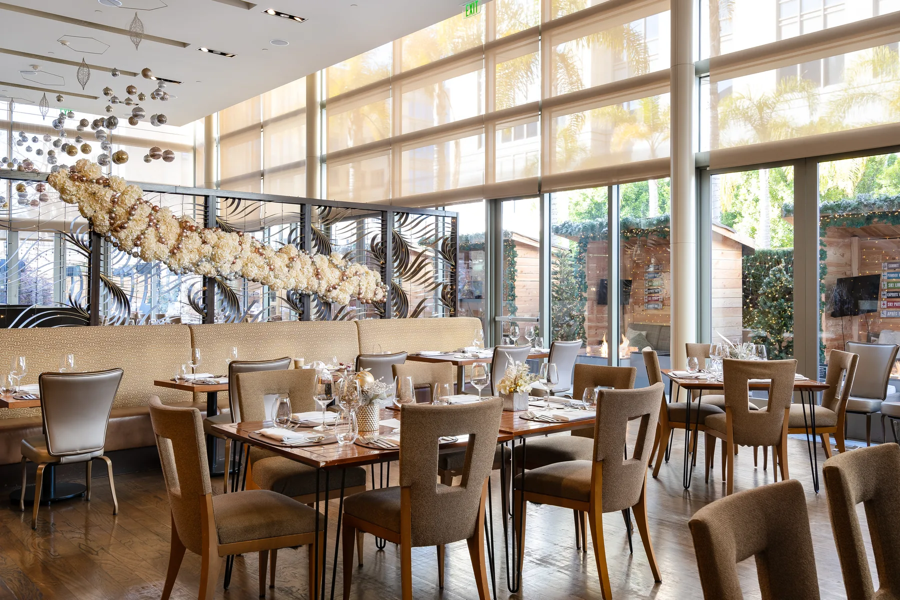 The Four Seasons Silicon Valley restaurant: set tables beneath a sculptural light installation, full-height glazing to the terrace