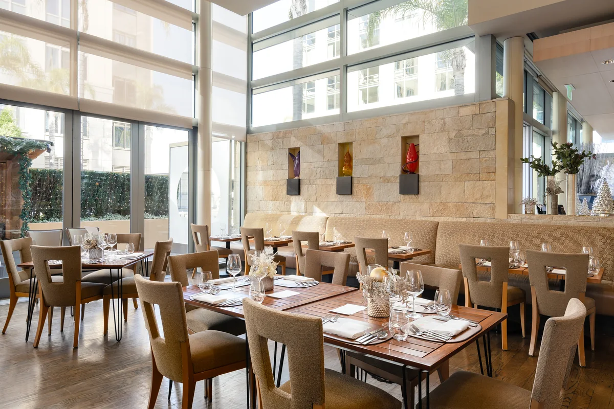 The restaurant at the Four Seasons Hotel Silicon Valley, East Palo Alto, tables set under tall windows.